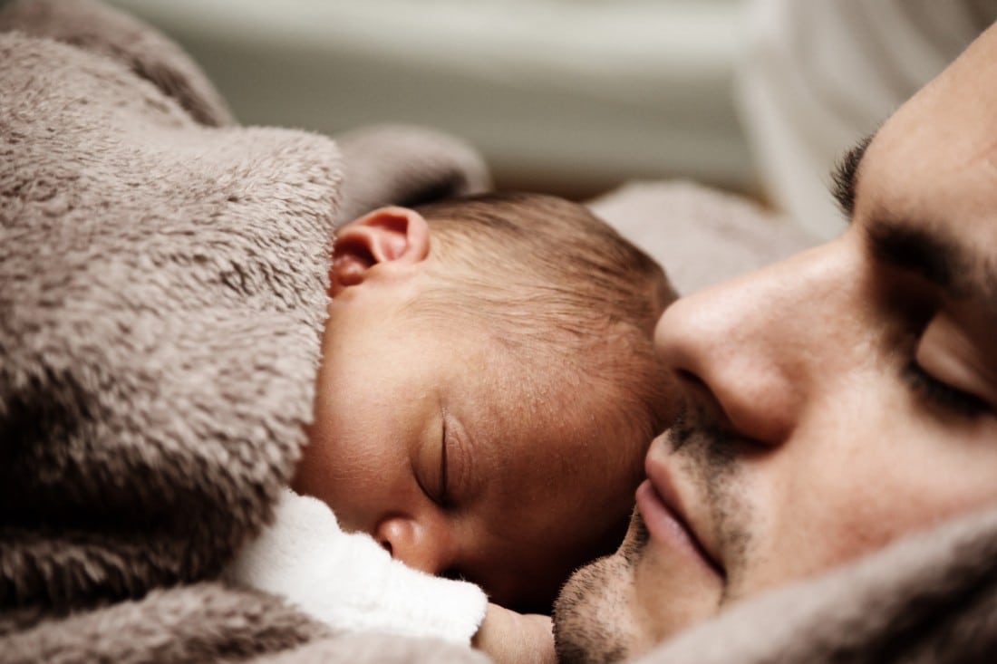 un papà con il suo bambino che dorme sul petto