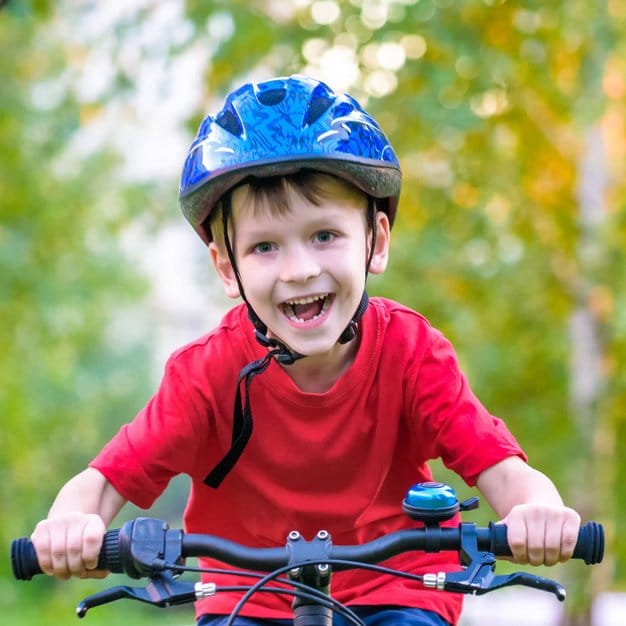 Un jeune enfant qui conduit son vélo tout en ayant un casque bleu sur sa tête