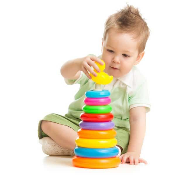Garçon mignon jouant avec tour coloré isolé