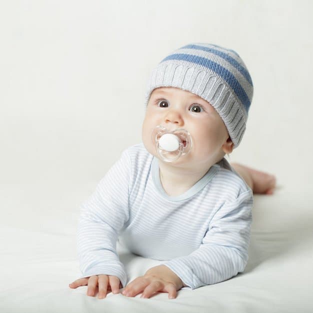bébé qui porte un bonnet avec une tétine blanche