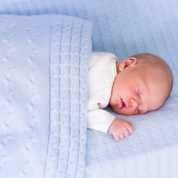 Nouveau né qui dort couvert d'une couette bleue