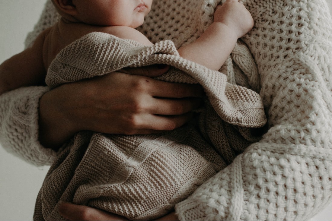 bambino in braccio alla mamma avvolto in una coperta