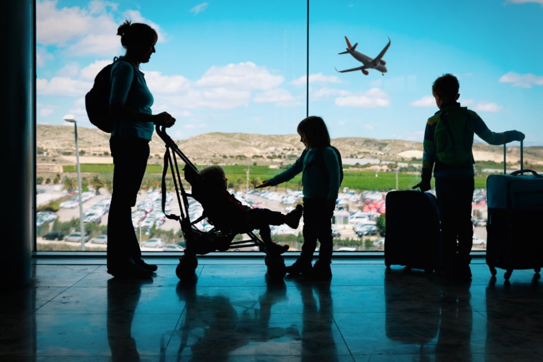 Una mamma in attesa in un aeroporto con i suoi bambini