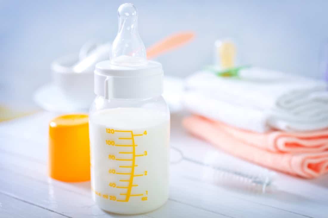 milk in a graduated bottle sitting on a changing table