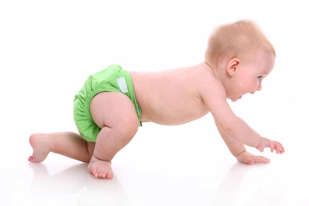 un bébé en couche réutilisable verte se déplace à 4 pattes