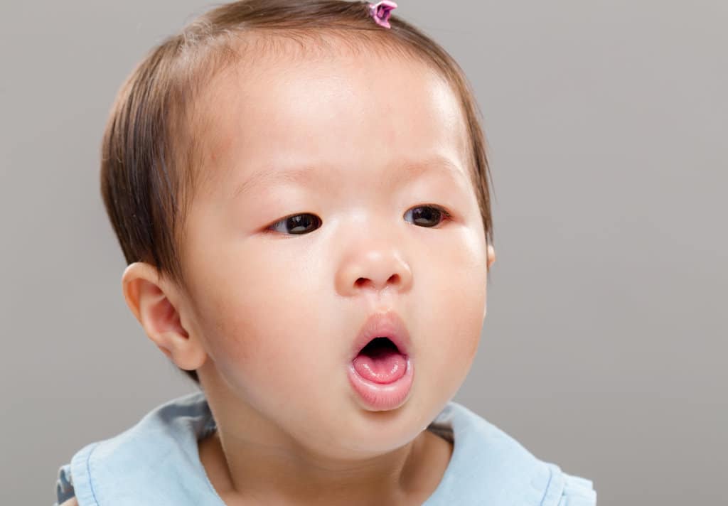 primo piano di un bambino che tossisce e tira fuori la lingua per tossire
