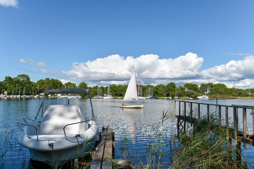 vista del lago di Biscarrosse davanti a un motoscafo al pontile e una barca a vela che naviga sul lago