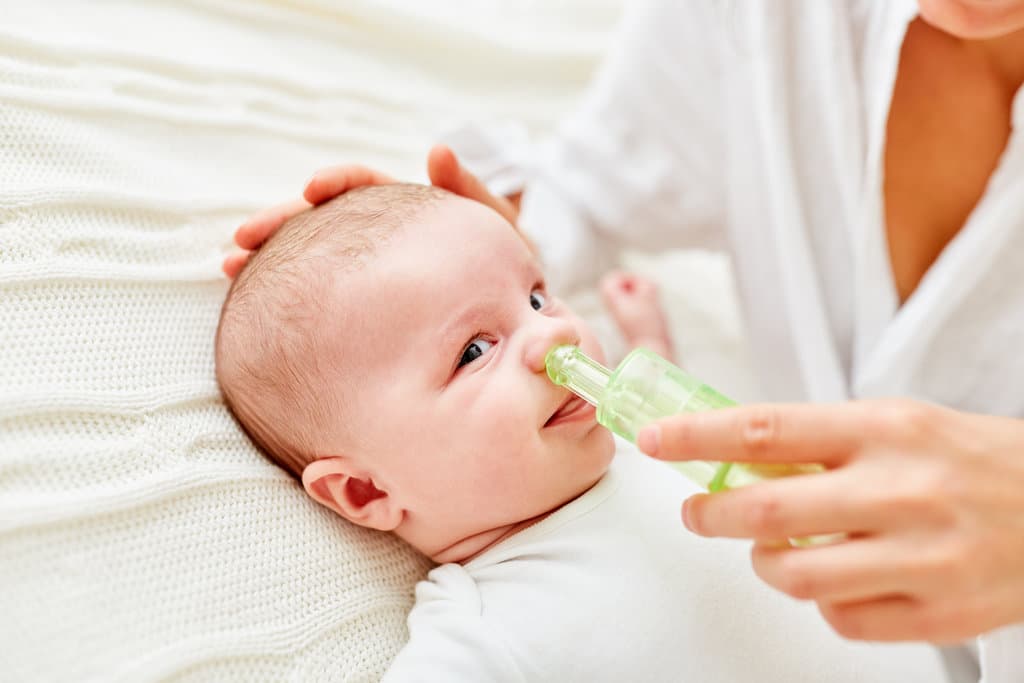 il naso di un bambino viene pulito con un aspiratore nasale