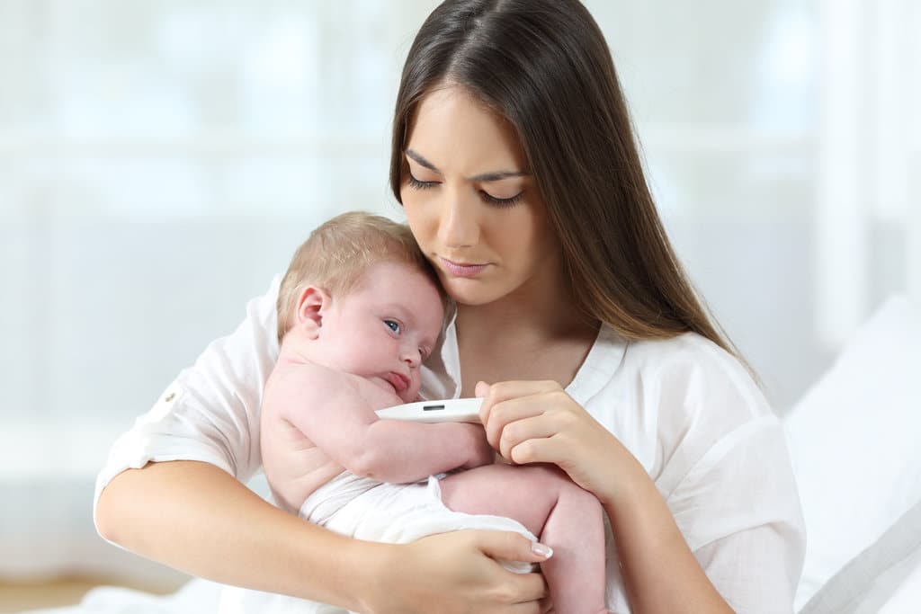 una madre tiene il suo bambino con un termometro